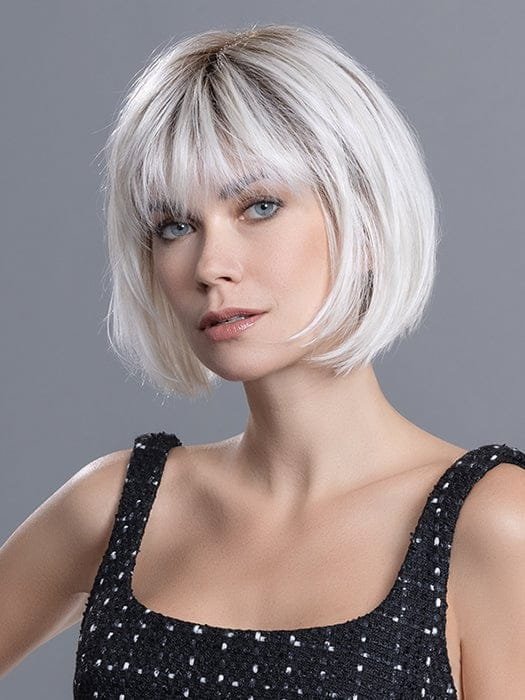 Model wearing short textured bob with bangs and natural root shading blonde synthetic wig Ellen Wille for modern style