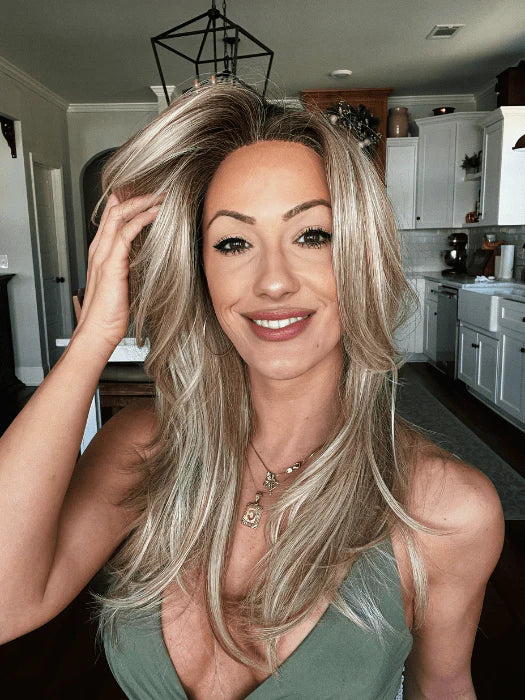 Woman smiling while wearing a long, stylish premium synthetic wig for women in a modern kitchen