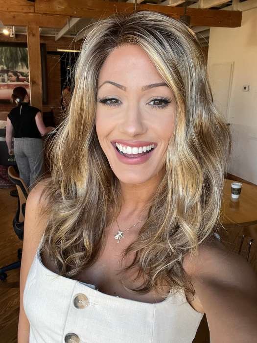 Smiling woman wearing Ellen Wille Arrow lace front wig in rooted blonde with loose waves natural hairline